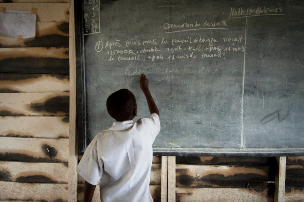 Boy writes on classroom chalkboard