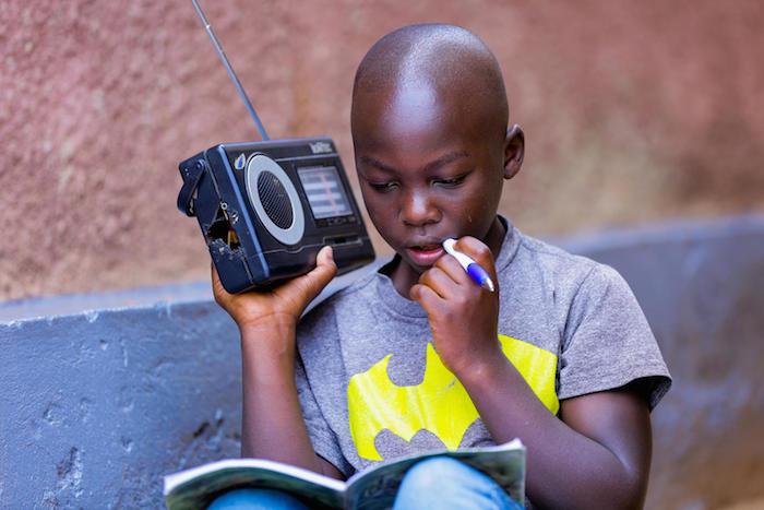 In Rwanda, a boy listens to a radio.